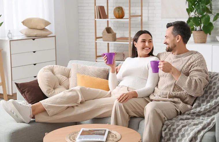 A happy couple in a bright, modern living room, smiling and enjoying a clean, organized space.